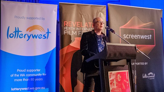 Richard Sowada speaks before signage from principal festival sponsors. 