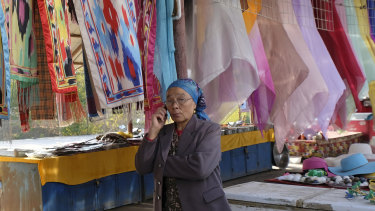 A souvenir vendor makes a call outside the Ermin Minaret in Turpan, Xinjiang.