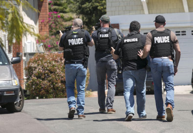 Heavily armed San Diego police officers approach a house thought to be the home of 19-year-old John T. Earnest.