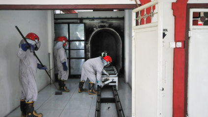 Workers check a cremation machine in Indonesia before cremating a COVID-19 victim.