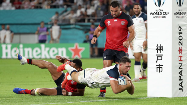 The USA's Bryce Campbell goes over the line to score his team's first try under a tackle from Joe Cokanasiga.