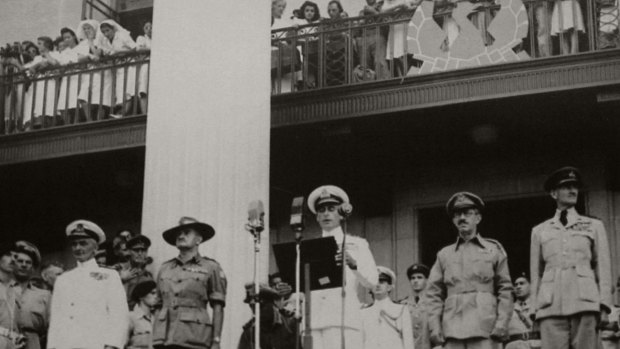 Sheila Bruhn in uniform peering over the balcony (left of pillar) at the City Hall as Lord Louis Mountbatten Supreme Allied Commander, South East Asia Command, at the podium addresses the surrender ceremony, September 12, 1945.