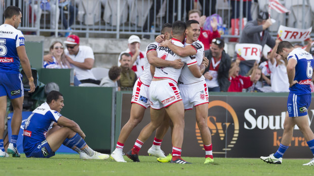 Down and out: Bulldogs players react after Tim Lafai scores one of the Dragons' seven tries on Sunday.