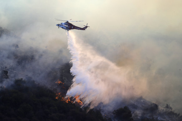 A helicopter drops water as the Getty fire burns in Mandeville Canyon.