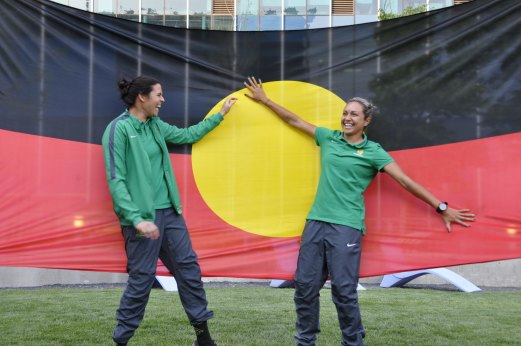 First Nations players Lydia Williams and Kyah Simon with the giant Aboriginal flag at the 2015 World Cup in Canada.