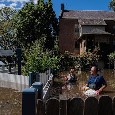 John and Sue Brookes cleaning up floating debris in the backyard of their Thompson Square home in Windsor. 
