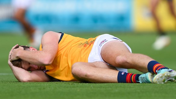 Adelaide’s Mark Keane holds his head after being concussed by Port’s Sam Powell-Pepper.