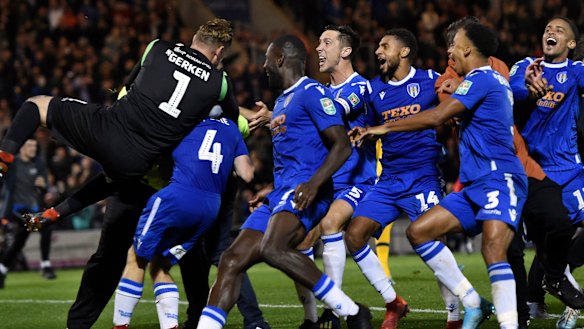 Bedlam: Colchester United's Tom Lapslie (4) is mobbed by teammates after scoring the winning penalty against Tottenham Hotspur at JobServe Community Stadium in Colchester.