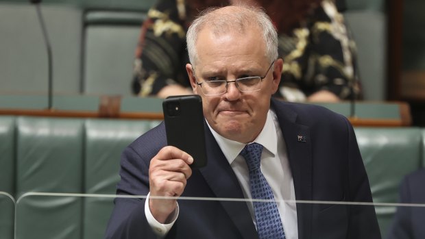 Prime Minister Scott Morrison holds up his phone during Question Time.