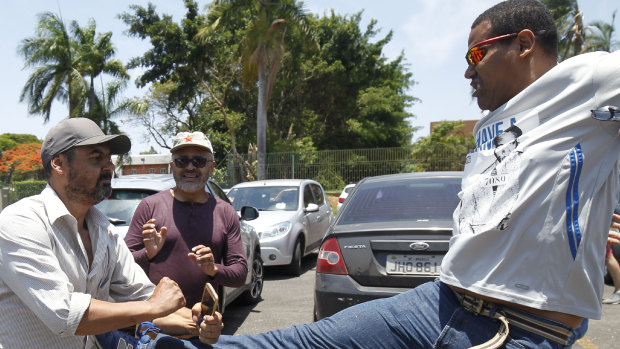 A supporter of Venezuelan President Nicolas Maduro kicks a supporter of Venezuelan opposition leader and self-proclaimed interim president Juan Guaido, outside the Venezuelan Embassy, in Brasilia.