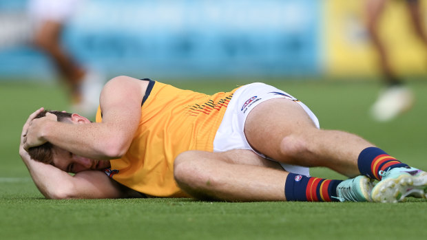 Adelaide’s Mark Keane holds his head after being concussed by Port’s Sam Powell-Pepper.