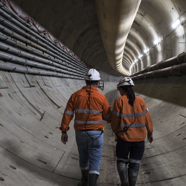 Construction workers walk through one of the 800-metre-long twin tunnels carved out of rock and sediment beneath Sydney Harbour. 