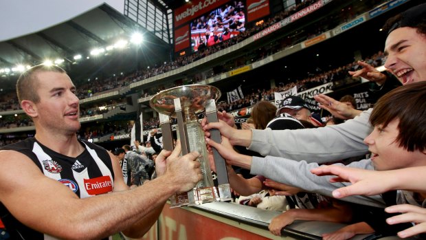 Magic moment: Magpies ruckman Darren Jolly takes the 2012 trophy to the Collingwood cheersquad.
