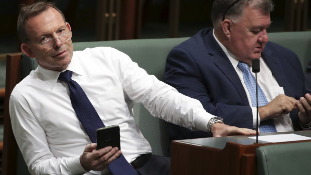 Tony Abbott and Craig Kelly use their mobile phones at Parliament House in Canberra. 