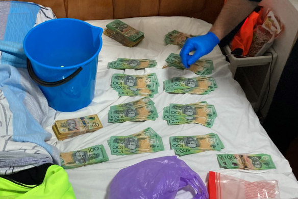 Australian Border Force officers with a bucket of cash in an ACT home linked to a group of Chinese nationals who were exploiting foreign workers on Sydney construction sites.