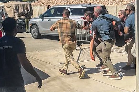 Security personnel carry Kirk to a car.