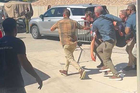 A screen grab from a video shows security personnel carrying Kirk after he was shot.