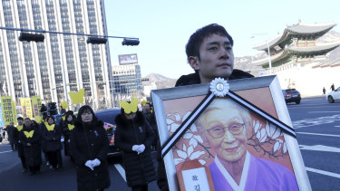 A mourner carries a portrait of the deceased Kim Bok-dong, during her funeral ceremony in Seoul on Friday.