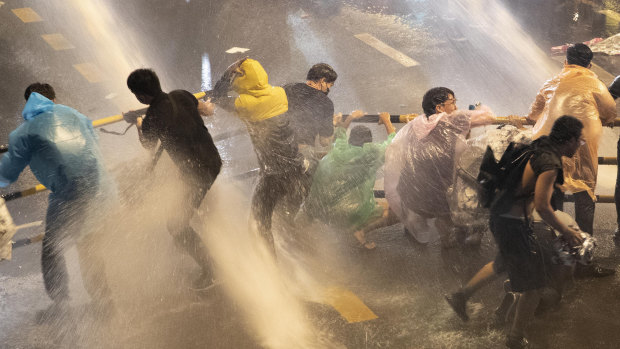 Protesters are hit with water canons as police try to clear an area in Bangkok on Friday, October 16.