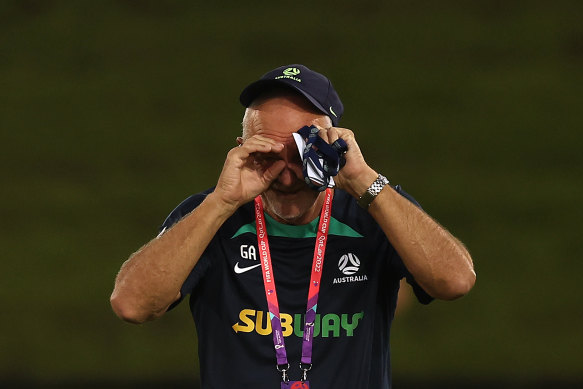 Graham Arnold jokes with the media pretending to use binoculars during Socceroos training in Doha.