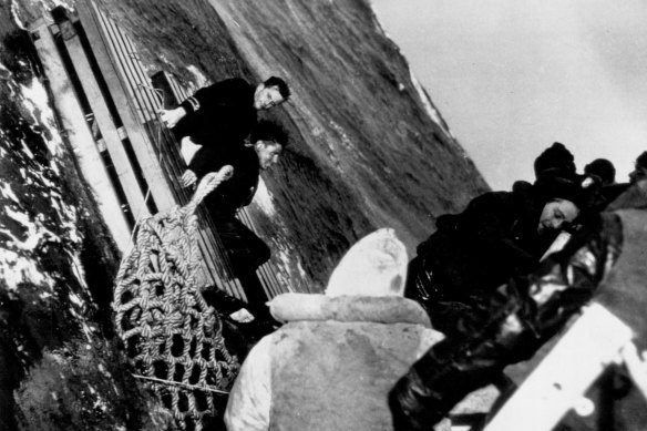 Two survivors of a torpedoed merchant ship wait to be taken on board a US coastguard ship in May 1943.