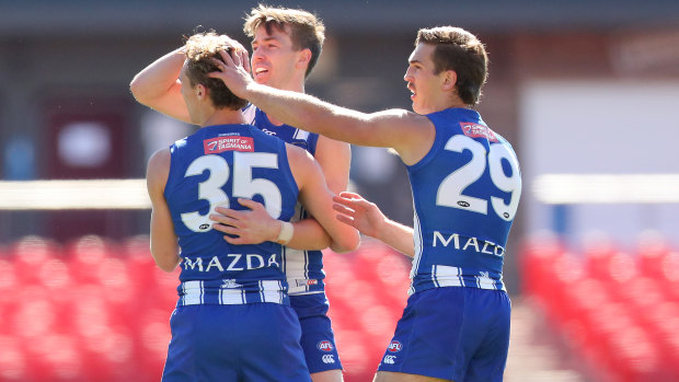 Charlie Lazzaro celebrates a goal with his North Melbourne teammates. 