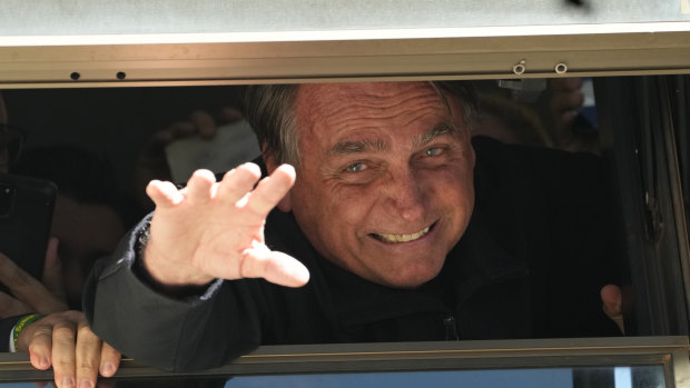 Brazil’s former president Jair Bolsonaro waves to supporters through a gap in the window at the Liberal Party’s headquarters in Brasilia, after returning from self-exile in Florida.