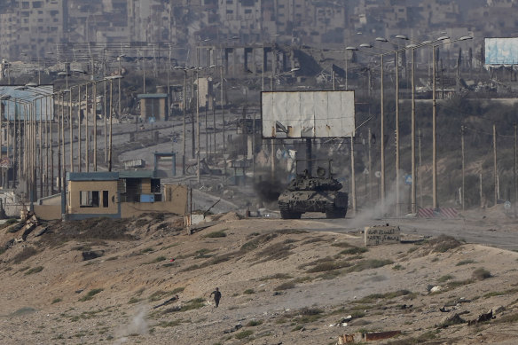 A Palestinian runs away from an Israeli tank in the central Gaza Strip on Sunday.