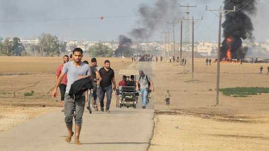 Palestinians walk away from the kibbutz of Kfar Azza, Israel, near the fence with the Gaza strip.