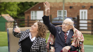 Captain Tom Moore with his daughter Hannah wave as a Spitfire and a Hurricane pass over his home to celebrate the veteran's 100th birthday. 