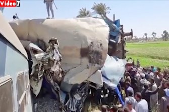 Crowds of people gather around wrecked train carriages after the crash in southern Egypt.