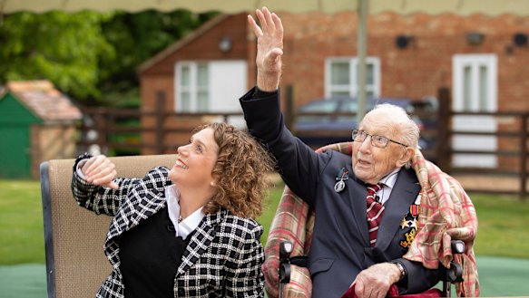Captain Tom Moore with his daughter Hannah wave as a Spitfire and a Hurricane pass over his home to celebrate the veteran's 100th birthday. 