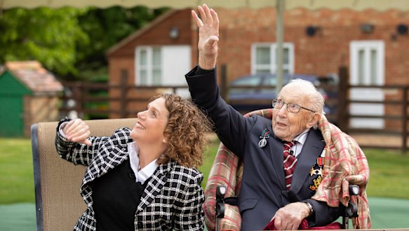 Colonel Tom Moore and his daughter Hannah wave as a Spitfire and a Hurricane pass over his home to celebrate the veteran's 100th birthday. 