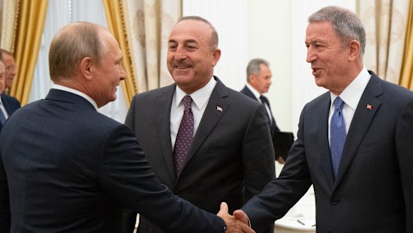 Russian President Vladimir Putin, left, greets Turkish Foreign Minister Mevlut Cavusoglu, centre, Turkish Defence Minister Hulusi Akar, during their meeting in the Kremlin in Moscow, Russia, on Friday.