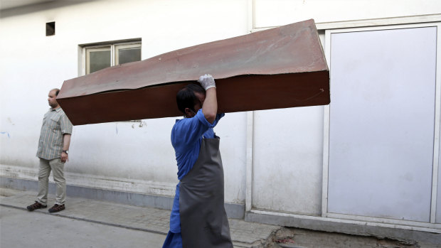 An Afghan man carries an empty coffin in the hospital following a deadly attack outside the Rural Rehabilitation and Development Ministry in Kabul, Afghanistan, on Sunday.