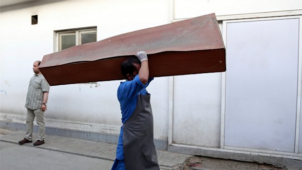 An Afghan man carries an empty coffin in the hospital following a deadly attack outside the Rural Rehabilitation and Development Ministry in Kabul, Afghanistan, on Sunday.