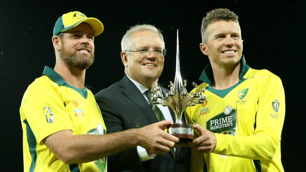 Prime Minister Scott Morrison holds the trophy with Dan Christian and Peter Siddle.