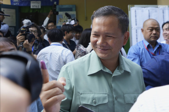 Hun Manet, of the Cambodian People’s Party, son of Cambodian Prime Minister Hun Sen, also army chief, shows off his inked finger outside a polling station after voting in Phnom Penh, Cambodia.