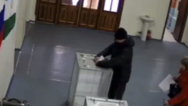 In this screen grab taken from video provide by the Central Election Commision  via Navalny Opposition Group on Sunday,  a man allegedly stuffs ballots into a ballot box at a polling station.