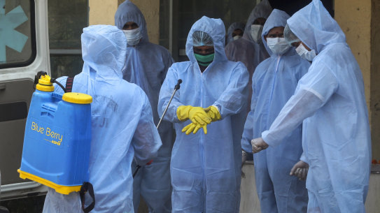 Municipal workers in protective suits sanitise themselves after cremating a COVID-19 victim in Mumbai on Thursday.