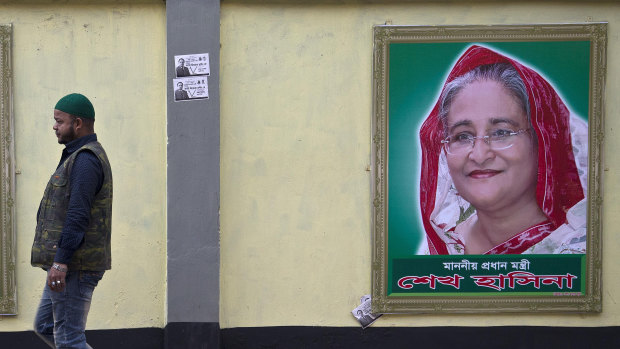 A man walks past a portrait of Bangladesh Prime Minister Sheikh Hasina on the eve of general elections in Dhaka.