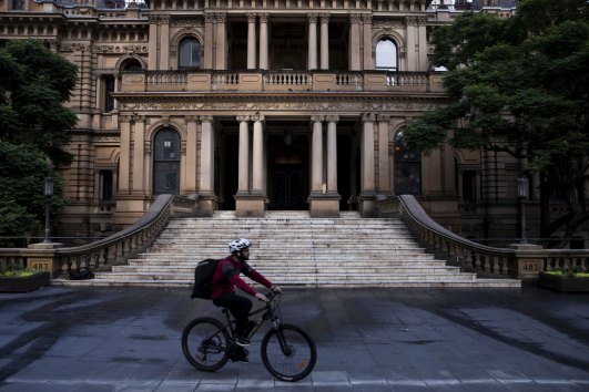 A delivery rider passes the City of Sydney Town Hall.