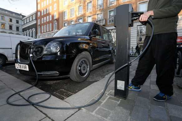 A London cab driver charges a TX City London taxi built by the London Electric Vehicle Company.
