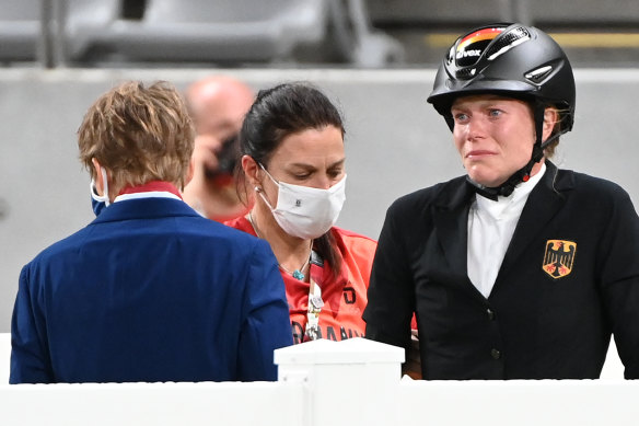German coach Kim Raisner (centre) and rider Annika Schleu following the incident involving horse Saint-Boy at the Tokyo Olympics.