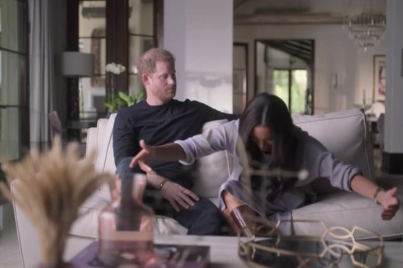 In a scene from their Netflix docuseries, Harry watches on while Meghan reenacts a curtsy.