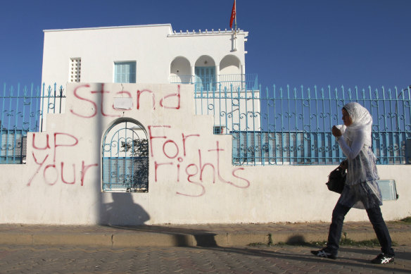 A woman walks past graffiti in Sidi Bouzid, Tunisia. The country has struggled to recover since the Arab Spring.