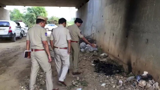 Indian police officers inspect the site where the woman's burned body was found.