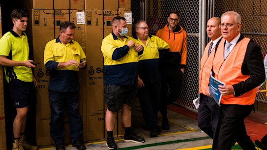 Prime Minister Scott Morrison walks past workers at the Rheem hot water system factory on Tuesday.