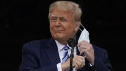 On one of the rare occasions he wore a mask in public, President Donald Trump removes it to speak from the Blue Room Balcony of the White House to a crowd of supporters in October.