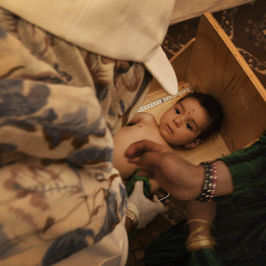 Qudratullah aged seven months has his height measured in a nutrition centre in Regreshan camp.